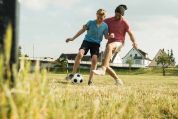 Vater und Sohn beim Fussballspielen auf Feld Vater und Sohn beim Fussballspielen auf Feld